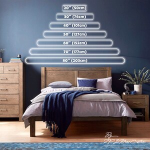 May include: A bedroom scene with a wooden bed frame, bedding, and a blue throw blanket. Above the bed, glowing white lines indicate bed sizes: 20" (50cm), 30" (76cm), 40" (101cm), 50" (127cm), 60" (152cm), 70" (177cm), and 80" (203cm).