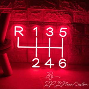 May include: A red neon sign shaped like a car's manual transmission gear shift pattern. The numbers 1, 2, 3, 4, 5, and 6 are visible, along with the letter "R" for reverse. The sign is against a brick wall. The text "By ZP Neon Custom" is at the bottom.