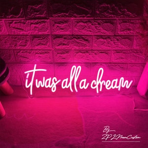 May include: A neon sign in a cursive font that reads "it was all a dream" in white against a pink background. The sign is illuminated, casting a pink glow. The words "By ZP Z Neon Custom" are at the bottom.