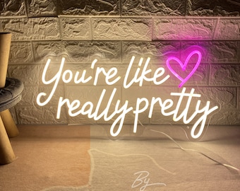 May include: A neon sign with the phrase "You're like really pretty" in white script, accompanied by a pink heart. The sign is against a textured brick wall.