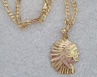 May include: A gold chain necklace with a pendant featuring a detailed profile of a Native American chief wearing a headdress. The chain is a curb style with a lobster clasp.