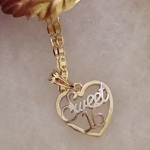 May include: Gold necklace with a heart-shaped pendant that says "Sweet 16" in a cursive font.