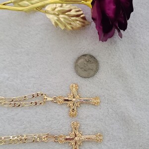 K&ouml;nnte beinhalten: Zwei goldfarbene Kreuzanh&auml;nger mit aufwendigen Details, jeweils an einer passenden Kette. Eine lila Rose mit goldfarbenen Bl&auml;ttern und eine US-Vierteldollarm&uuml;nze sind ebenfalls vorhanden. Ein Lineal mit dem Text "Made in U.S.A." ist sichtbar.