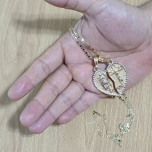 May include: Two gold necklaces with a heart-shaped pendant that is split in half. The pendant has the words "Te Amo" and "I Love You" inscribed on it.