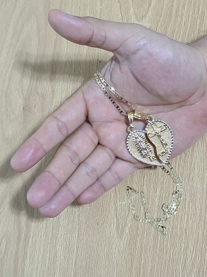 May include: Two gold necklaces with a heart-shaped pendant that is split in half. The pendant has the words "Te Amo" and "I Love You" inscribed on it.