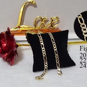 May include: Two gold Figaro chains on a black velvet cushion. The chains are available in 20", 22", and 24" lengths.  Figaro Chain 20" inches 22" inches 24" inches