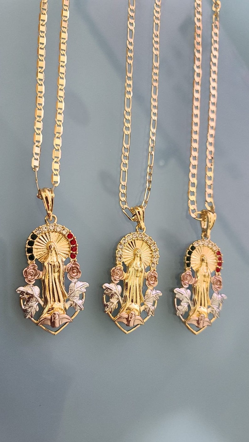 May include: Three gold chains with pendants featuring a religious figure, surrounded by roses and leaves. The pendants are made of gold, silver, and rose gold.