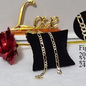 May include: Two gold Figaro chains on a black velvet cushion. The chains are available in 20", 22", and 24" lengths.  Figaro Chain 20" inches 22" inches 24" inches