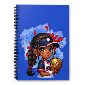May include: Spiral-bound notebook with a blue cover featuring a cartoon illustration of a softball player. The player is wearing a navy blue visor and uniform, holding a softball and glove. The background has blue and red paint splatters.