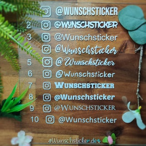 Op de afbeelding: Een transparant acryl bord met witte nummers van 1 tot en met 10 en Instagram-pictogrammen. Elk nummer is gekoppeld aan de tekst "@Wunschsticker" of "WUNSCHSTICKER". Het bord bevindt zich op een houten oppervlak.