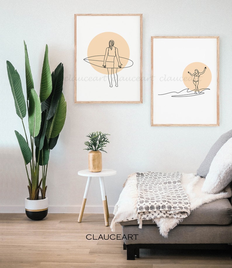 Pu&ograve; includere: Due stampe minimaliste di arte lineare di una donna che fa surf. Le stampe sono incorniciate in legno naturale e hanno uno sfondo bianco con un cerchio color pesca dietro la surfista. Le stampe sono appese a un muro bianco.