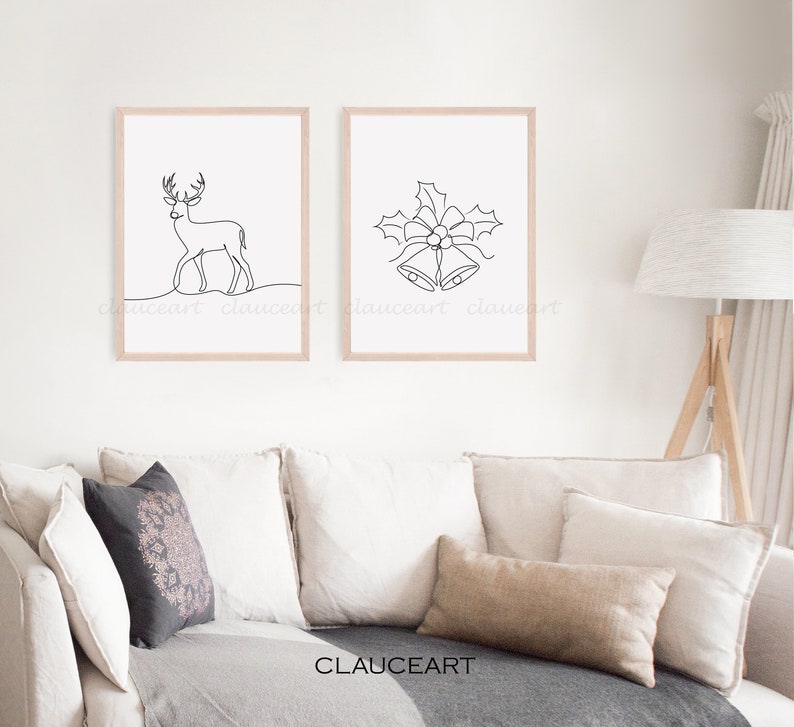 May include: Two minimalist line art prints in wooden frames. The print on the left depicts a deer, while the print on the right shows a pair of bells with a bow and holly leaves.