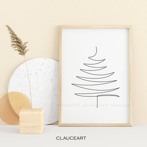 May include: A black and white line drawing of a stylized Christmas tree in a simple wooden frame. The frame is on a white surface with a beige background.