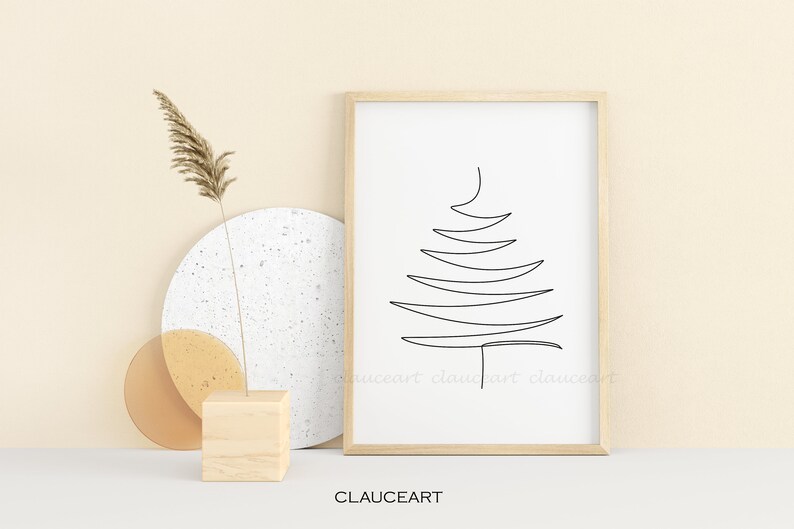 May include: A black and white line drawing of a stylized Christmas tree in a simple wooden frame. The frame is on a white surface with a beige background.