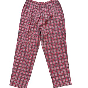May include: Red and black plaid pajama pants. The pants have an elastic waistband and a relaxed fit. The plaid pattern is made up of red, black, and white lines. The pants are made of a soft, lightweight fabric.