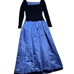 Könnte beinhalten: Vintage Abendkleid mit einem schwarzen Samt-Oberteil und langen Ärmeln, mit eckigem Ausschnitt. Der Rock ist aus fließendem, plissiertem blauem Satin. Das Kleid hat eine klassische, elegante Silhouette, geeignet für besondere Anlässe.