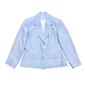 Op de afbeelding: Een lichtblauwe blazer met een revers, twee voorzakken en drie knopen. De blazer heeft lange mouwen en een getailleerde pasvorm. Het label luidt "ATELIER MODE".