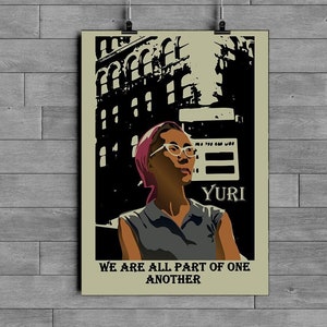 May include: A vintage-style poster featuring a woman with glasses and a pink headscarf. The poster has a black and white cityscape background with the text "YURI" and "WE ARE ALL PART OF ONE ANOTHER".