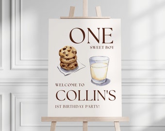 May include: A white sign with brown text that reads "ONE SWEET BOY WELCOME TO COLLIN'S 1ST BIRTHDAY PARTY!"  The sign also features a watercolor illustration of a stack of chocolate chip cookies and a glass of milk.