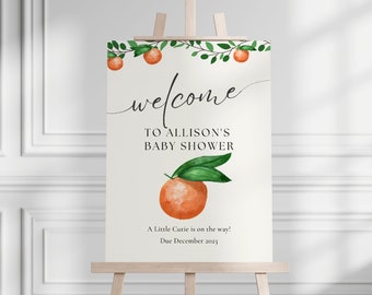 May include: Welcome sign for a baby shower with a watercolor illustration of an orange and green leaves. The text reads "Welcome to Allison's Baby Shower. A Little Cutie is on the way! Due December 2023."