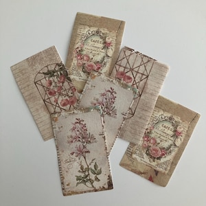 May include: Five vintage style paper cards with floral designs and text. The cards are beige and brown with pink and white flowers. The text on the cards reads "Cafe's Le Limonadier".