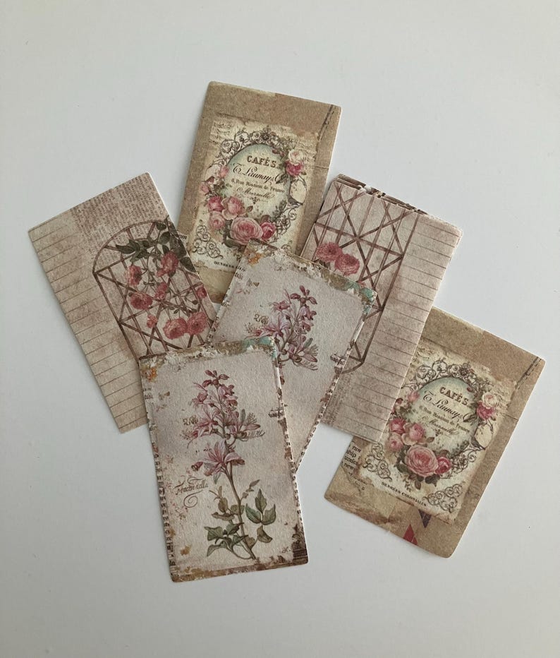 May include: Five vintage style paper cards with floral designs and text. The cards are beige and brown with pink and white flowers. The text on the cards reads "Cafe's Le Limonadier".