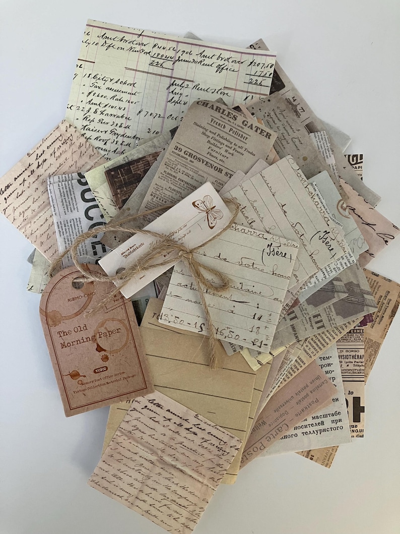 May include: A stack of vintage paper ephemera with handwritten notes, old newspaper clippings, and a tag that reads "The Old Morning Paper". The papers are tied together with twine and a decorative butterfly tag.