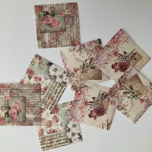 May include: A set of eight vintage-style paper squares with floral designs. The squares feature a variety of floral patterns, including roses, daisies, and other delicate flowers. The paper is textured and has a distressed look, giving it a vintage feel.