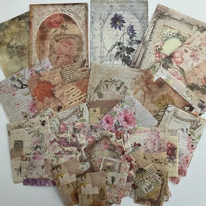 May include: A collection of vintage-style paper ephemera featuring floral designs, handwritten text, and delicate patterns. The papers are in shades of cream, brown, and pink, with a distressed, aged look.
