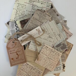 May include: A stack of vintage paper ephemera with handwritten notes, newspaper clippings, and a tag that reads "The Old Morning Paper". The papers are tied together with twine and have a rustic, aged look.