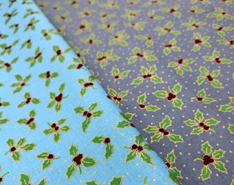 May include: Two pieces of fabric with a repeating holly leaf pattern. One fabric is light blue, the other is gray. The holly leaves are green with brown berries and gold outlines. The background has small white dots.