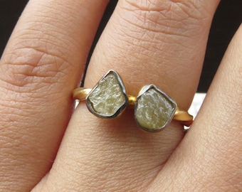 May include: A gold ring with two raw, light yellow gemstones set in silver.