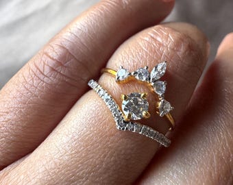 May include: Three rings are displayed, showcasing a variety of designs. The rings feature clear gemstones set in gold and silver bands. One ring has a central round stone, another has a V-shape, and the third has a floral design.
