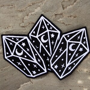 May include: Three black and white embroidered iron-on patches shaped like crystals with a crescent moon and stars inside.