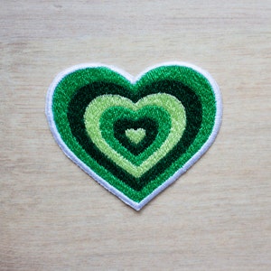 May include: A green heart-shaped patch with concentric circles of green and light green embroidery.