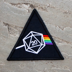 May include: A black triangular patch with a white 20-sided die and a rainbow prism. The die has the number "20" on it.