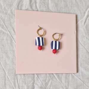 Beaded huggie hoops in navy blue and white stripe with red bead, handmade polymer clay earrings