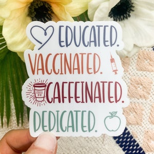 May include: White sticker with the text "Educated. Vaccinated. Caffeinated. Dedicated."  A heart, a syringe, a coffee cup, and an apple are included in the design.