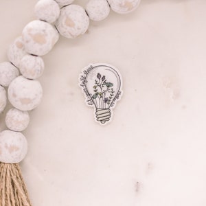 May include: A white light bulb sticker with a floral design inside and the text "Let your light shine" around the bulb.