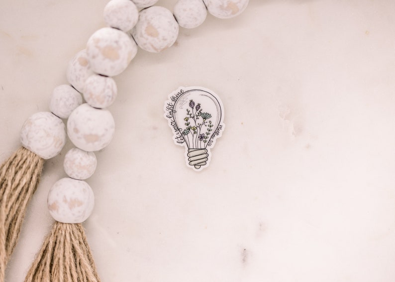 May include: A white light bulb sticker with a floral design inside and the text "Let your light shine" around the bulb.
