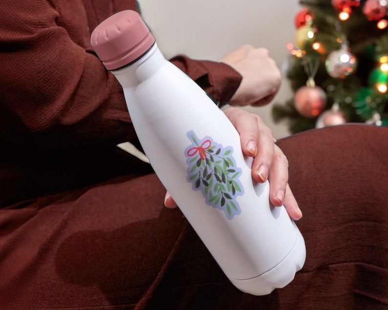 May include: White insulated water bottle with a pink lid and a sticker of a sprig of mistletoe with a red bow.