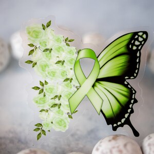 May include: Green butterfly with a green ribbon and white flowers on a clear background.