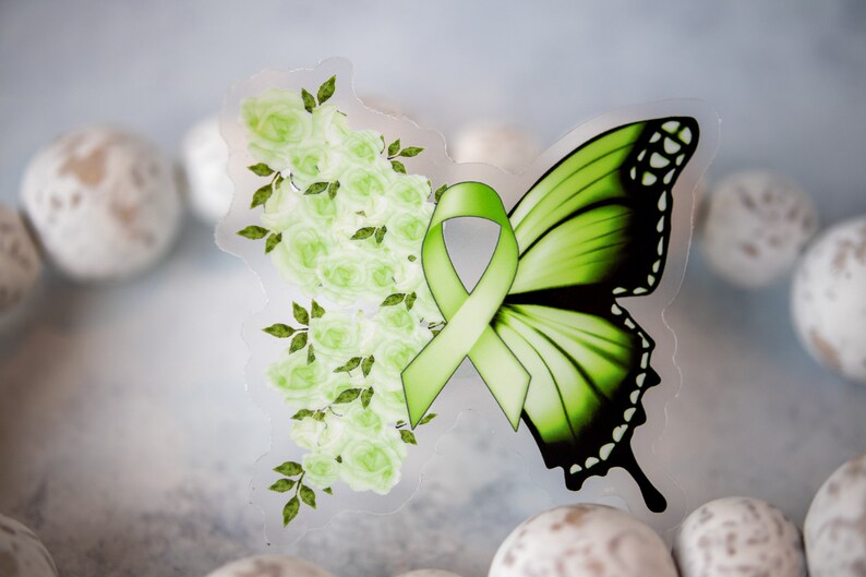 May include: Green butterfly with a green ribbon and white flowers on a clear background.