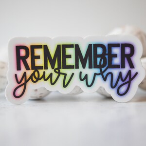 May include: A white sticker with a rainbow gradient behind the text "Remember your why" in black.