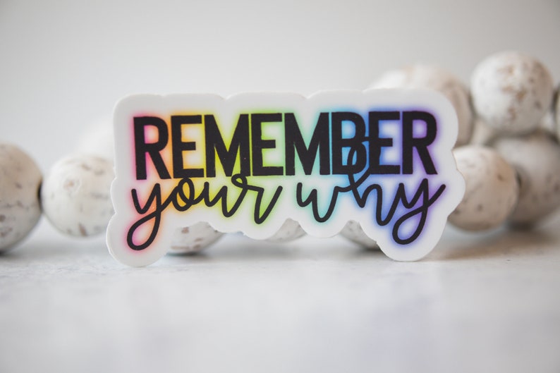 May include: A white sticker with a rainbow gradient behind the text "Remember your why" in black.