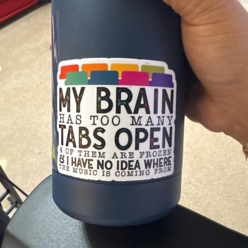 May include: A blue reusable water bottle with a sticker that says "My brain has too many tabs open & I have no idea where the music is coming from".