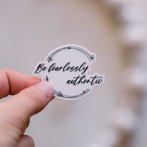 May include: White sticker with a black circle and the text "Be fearlessly authentic" inside.