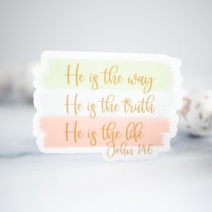 Pode incluir: Um adesivo com fundo verde pastel, branco e p&ecirc;ssego. O adesivo apresenta o texto "He is the way, He is the truth, He is the life, John 14:6" em letras douradas.