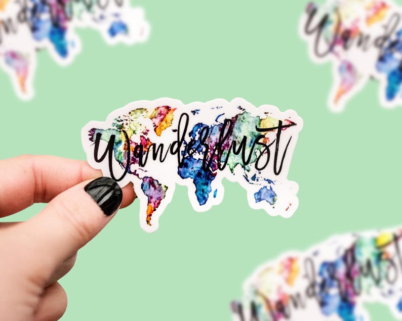 May include: A sticker with a watercolor world map design in vibrant colors, including blue, purple, yellow, and orange. The word "Wanderlust" is written in black script across the map. Additional stickers with the same design are visible in the background.
