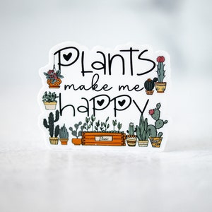 May include: White sticker with the text "Plants make me happy" in black lettering with two small hearts. The sticker features a variety of potted plants and cacti in a row.